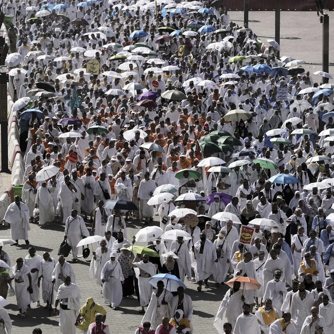 Hajj pilgrims walking with umbrellas during pilgrimage preparation and travel