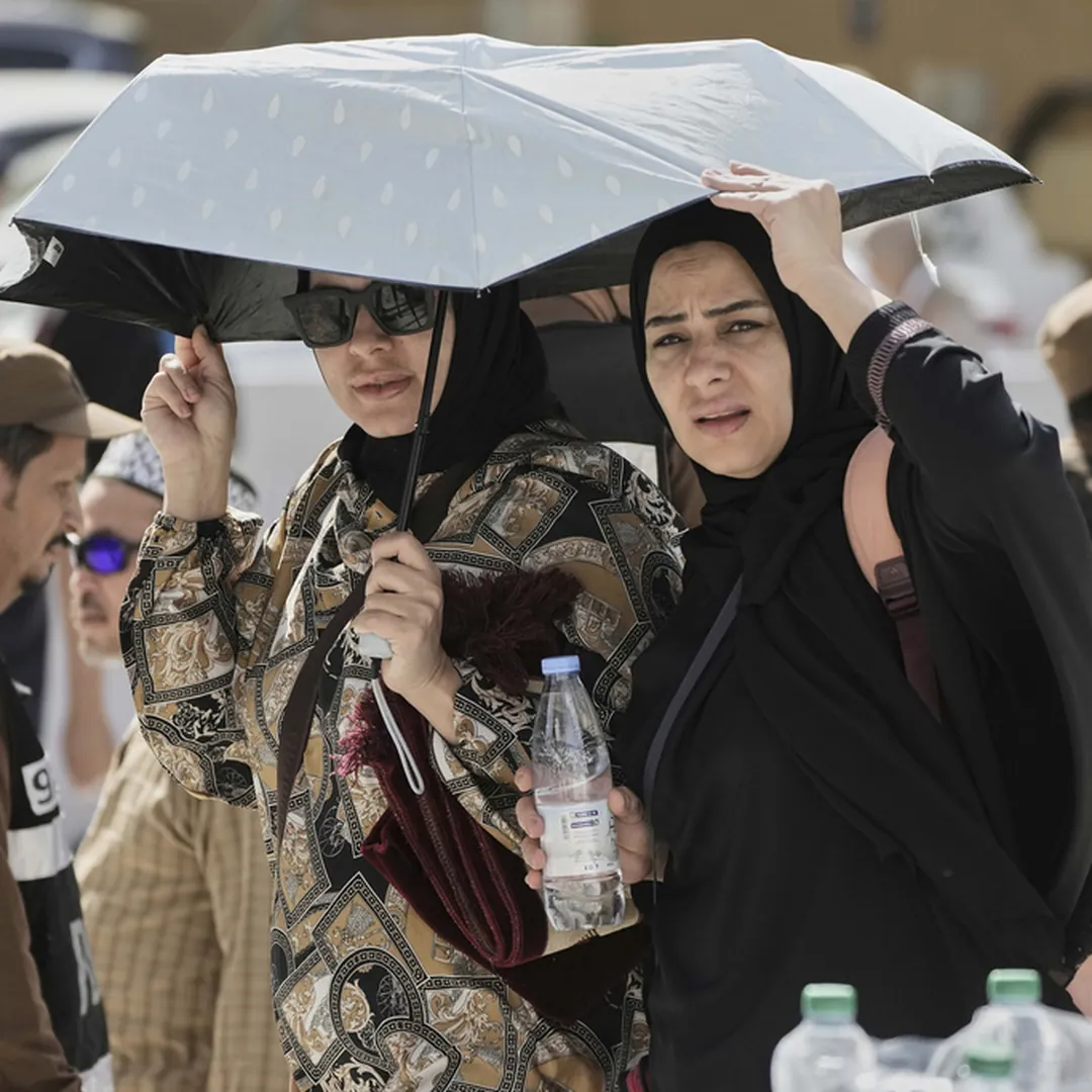 Women Hajj pilgrims under umbrellas during hot weather conditions in Saudi Arabia